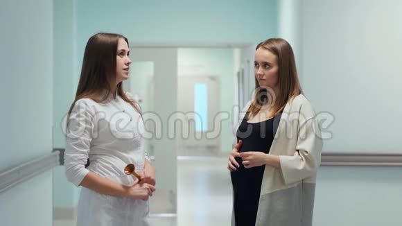 一位女医生和一位年轻的孕妇站在移植中心的走廊里医生问视频的预览图
