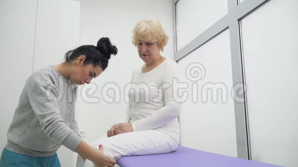 医生检查老年妇女的膝盖和腿视频的预览图