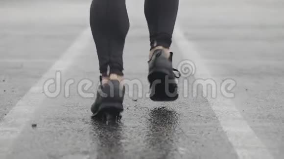 运动鞋跑步者腿的慢动作镜头男运动员在户外慢跑多雨的单跑道视频的预览图