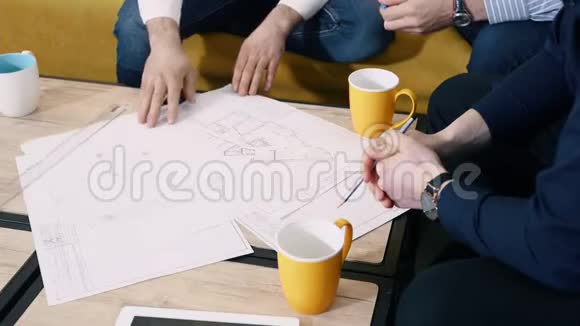 一群人在办公室里用图纸工作纠正不准确之处手放在桌子上特写视频的预览图