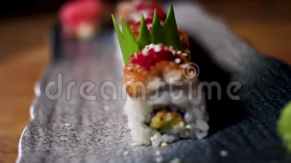 靠近日本寿司卷在一个黑色盘子站在木桌上食品店的概念框架新鲜美味可口视频的预览图