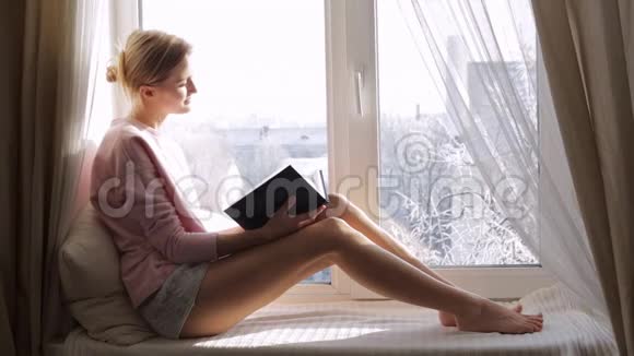 梦中的女人拿着一本书坐在窗台上透过窗户看着视频的预览图