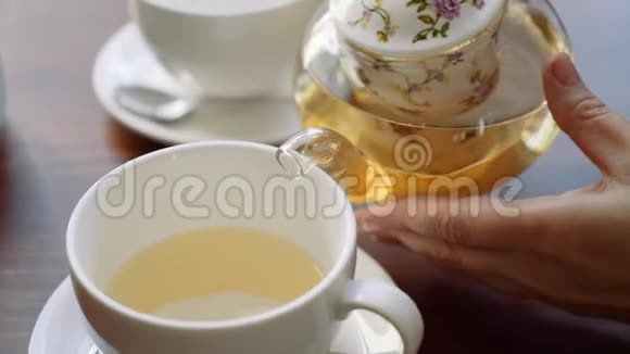 女孩在杯子特写中倒茶视频的预览图