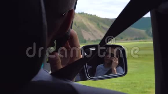 从汽车后座上看到一个年轻人反射在后视镜上视频的预览图