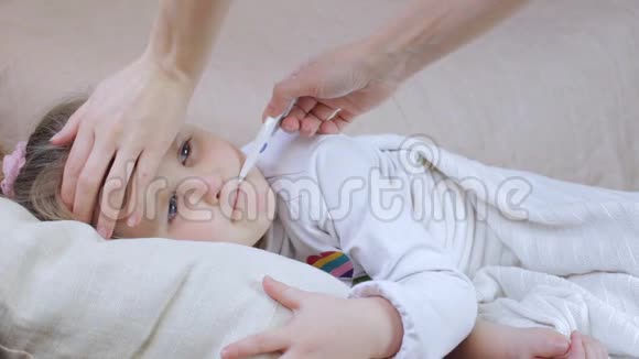 带体温计的生病女孩妈妈摸了摸她的头视频的预览图