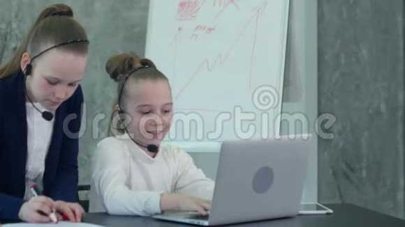 在办公室工作忙的女孩用笔记本电脑和耳机视频的预览图