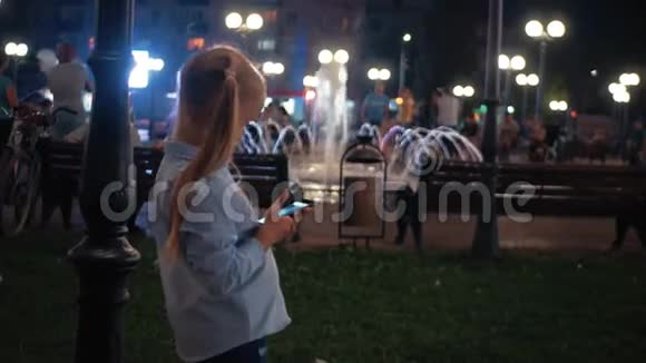 少女在城市里晚上使用智能手机视频的预览图