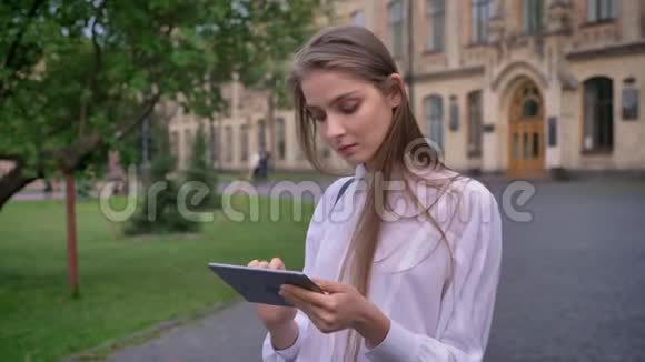 年轻有魅力的女学生在夏天的平板电脑上工作看着摄像机交流理念视频的预览图