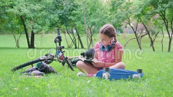 美丽的少女在草地上的公园里读书视频的预览图