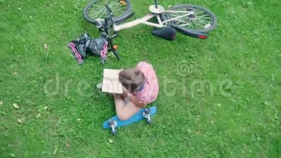 公园里坐在草地上看书的顶景女孩视频的预览图