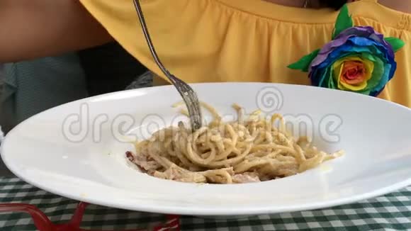 穿黄色连衣裙的女人正在吃一个白酱意大利面视频的预览图