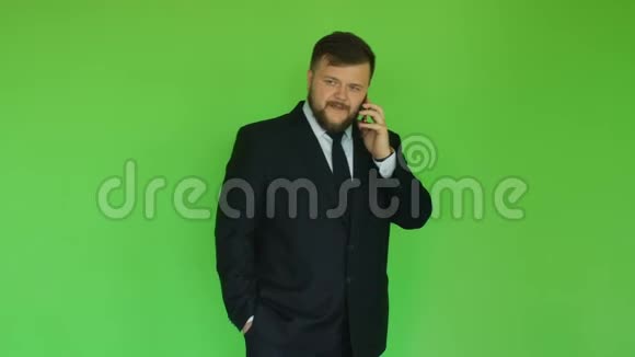 长胡子的胖商人穿着夹克和领带在智能手机上聊天铬绿色有钱人通过电话解决问题视频的预览图