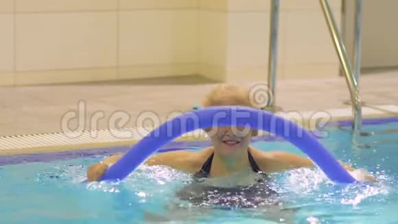 微笑的老妇人在游泳池里用面条做运动视频的预览图