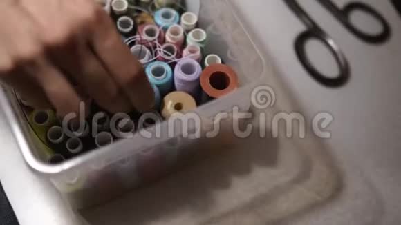 一盒缝纫线卷筒时尚设计师男子手挖在组织者充满不同色彩的线视频的预览图