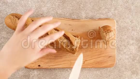女性的手正在木切割板上切新鲜的黑麦面包视频的预览图