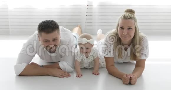 幸福的一家人躺在客厅的白色地板上视频的预览图