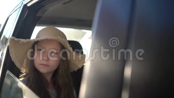快乐美丽的女孩带着草帽在汽车后座旅行公路旅行概念视频的预览图