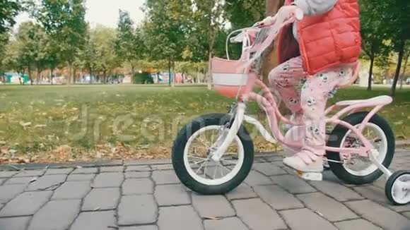 公园里骑粉色自行车的女孩视频的预览图