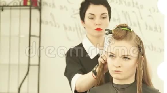 女理发师在美容院理发时使用夹子固定头发关闭剪发师修理女性视频的预览图