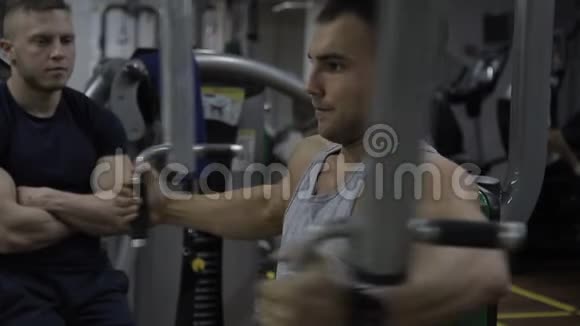 男性健美运动员正在健身房锻炼手臂肌肉他的沙发控制着他的训练视频的预览图