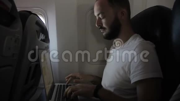 年轻人坐在飞机上用笔记本电脑工作视频的预览图
