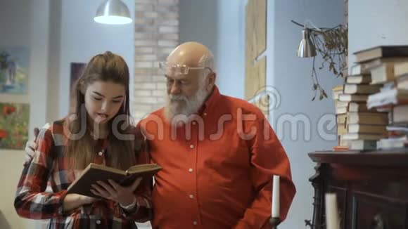 年轻漂亮的女孩和祖父一起读有趣的书视频的预览图