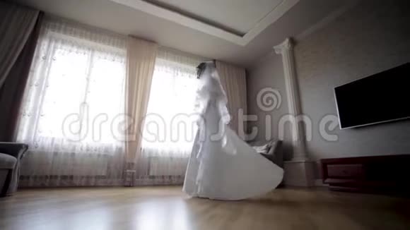 漂亮的新娘穿着婚纱在家里转悠大窗户的背景视频的预览图