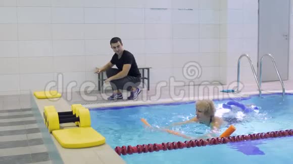 教练带着面条向游泳池里的老女人展示运动视频的预览图