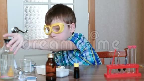 家庭化学实验男孩拿一瓶水用吸管把水倒进管子里前景视频的预览图