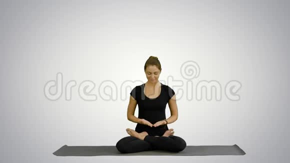 年轻女子在白色背景下练习瑜伽时进行冥想视频的预览图
