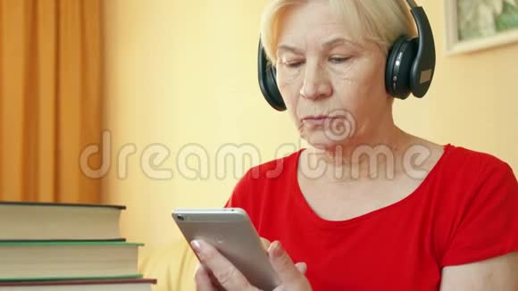 高级女性使用应用程序听力技能培训在智能手机上学习外语视频的预览图