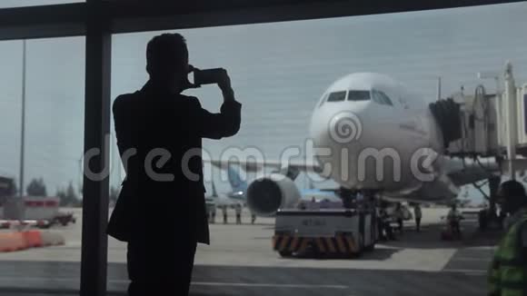 在机场拍摄飞机通过窗户的人的剪影视频的预览图