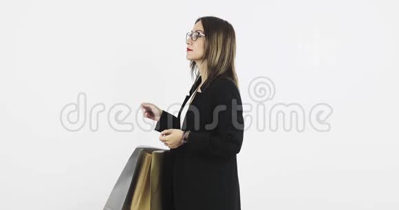 一个快乐的年轻商务女性拿着很多购物袋办公室里有一件新衣服视频的预览图