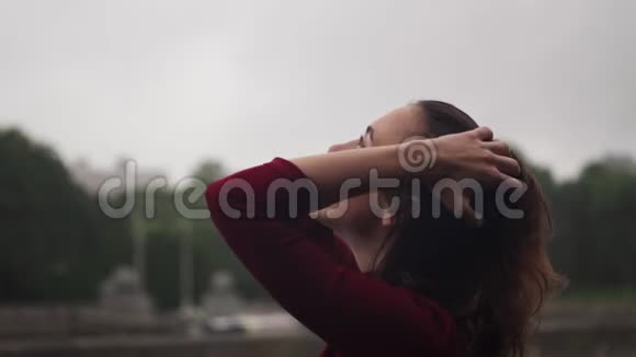 年轻快乐性感的女人抬头看着雨抚摸着湿发的头视频的预览图