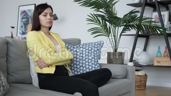头痛的休闲妇女在家坐在沙发上视频的预览图