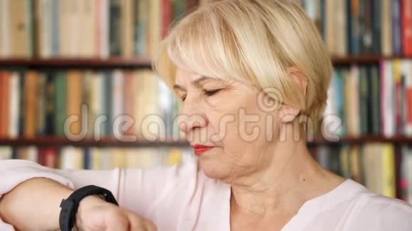 老妇人在家里口授信息在智能手表上聊天背景书架视频的预览图