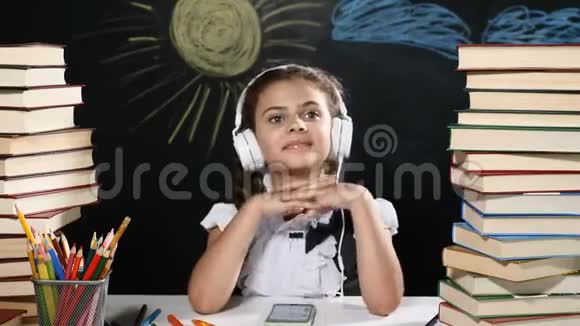 现代学校观念漂亮的女孩坐在一张桌子上手里拿着一堆书还有她身后的黑板女学生视频的预览图