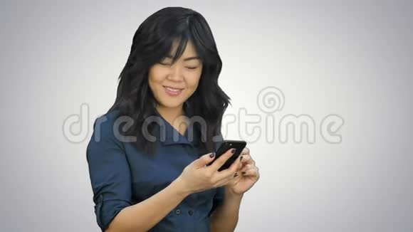积极的年轻美丽的亚洲女人使用手机跳舞和微笑的白色背景视频的预览图
