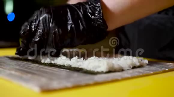 厨师把米饭放在诺里片上日本菜的概念框架戴上黑色的烹饪手套视频的预览图