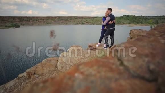 一对夫妇拥抱在一个大湖的悬崖附近视频的预览图