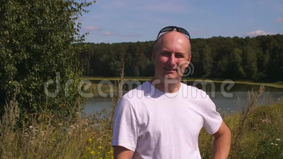 一位成年男子微笑着在夏天的森林里与湖一起看镜头视频的预览图