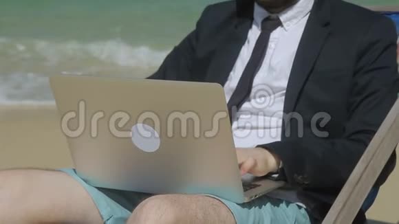 商人正在海滩上用电脑打商务邮件视频的预览图