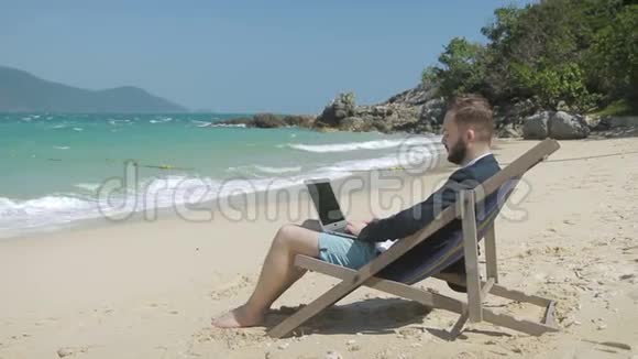 成功的商人用笔记本电脑在外面的海滨工作视频的预览图