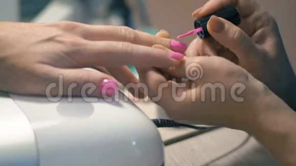 美甲大师特写将粉色漆涂在女手上视频的预览图