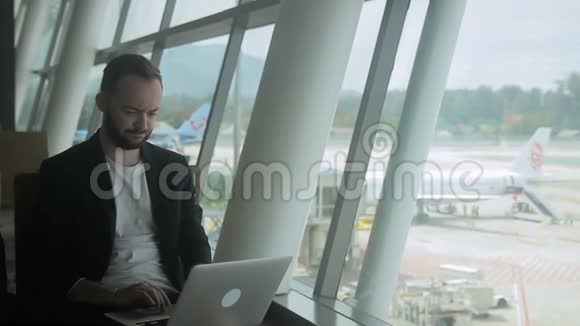 在机场男人在旅行中使用互联网在笔记本电脑上做生意视频的预览图