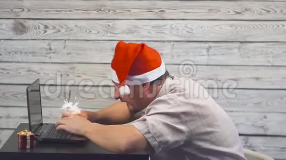 有圣诞老人标志的英俊男子正在使用笔记本电脑并在闪烁的火焰中欢欣鼓舞视频的预览图