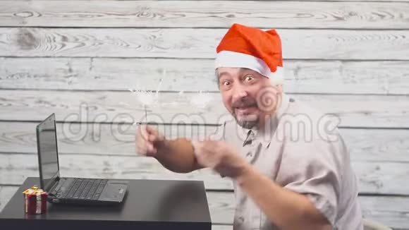 有圣诞老人标志的英俊男子正在使用笔记本电脑并在闪烁的火焰中欢欣鼓舞视频的预览图