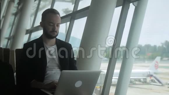 成功的商人在机场等待航班时使用笔记本电脑视频的预览图