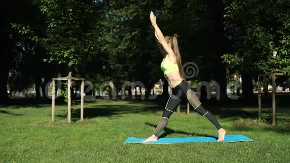 活跃的女性在草地上的城市公园锻炼和伸展瑜伽视频的预览图