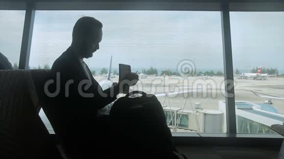 年轻人的剪影他正在机场等待他的航班起飞视频的预览图